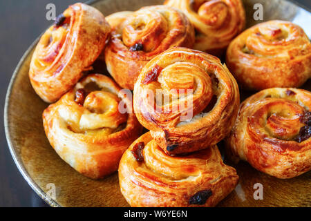 Delicicous golden braun Schmerz aux Rosinen oder Raisin wirbelt, typisch dänische und französische Backwaren, auf einer Platte. Stockfoto