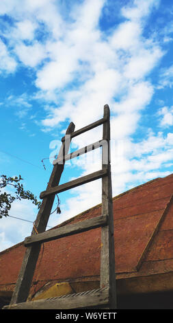 Ansicht von unten auf das hölzerne Treppe an der Seite des Daches vor einem blauen bewölkten Himmel, selektiven Fokus Stockfoto