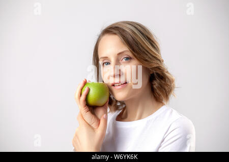 Lächelnd schöne Frau mit einem Apple auf grauem Hintergrund Stockfoto