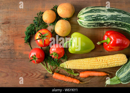 Eine Reihe von Gemüse auf einem hölzernen Tisch gelegt. Flach, Ansicht von oben. Freier Platz für Text. Stockfoto