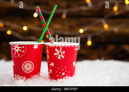 Zwei festliche Weihnachten Papier red Cups mit Getränk im Schnee auf hölzernen Hintergrund Stockfoto