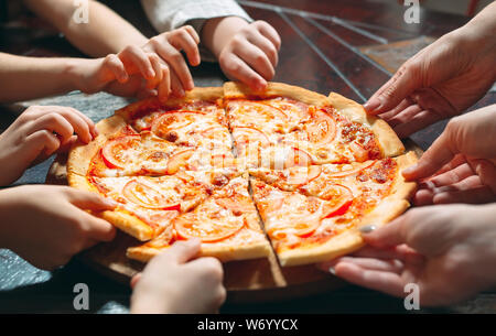 Hände, die pizza Scheiben aus Holz- Tabelle, Ansicht schließen. Stockfoto