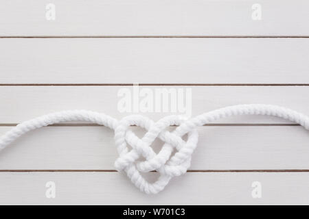 Herz geformte Knoten auf weißem Holz- Hintergrund Stockfoto