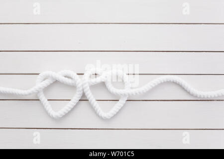 Herz geformte Knoten auf weißem Holz- Hintergrund Stockfoto