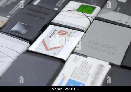 Charkow, Ukraine - Juli 30, 2019: Haufen alter verwendet Handy Akkus. Recycling von Elektronik wurde verkauft auf dem Markt billig. Nahaufnahme, Ansicht von oben Stockfoto