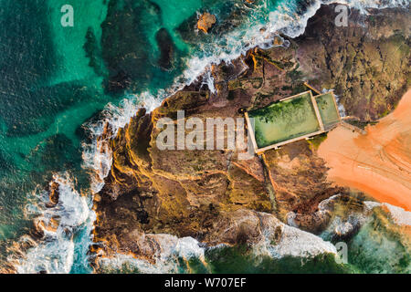 Mona Vale rock Pool an der Spitze der Sandsteinfelsen aus breiten Sandstrand in Sydney während Soft morgen Licht gesehen von oben nach unten von oben. Stockfoto