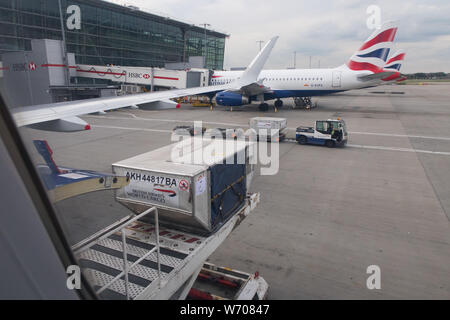 Gepäck handers Gepäck Fracht von Behältern von einem britischen Flugzeug Airways in London Heathrow Terminal 5 entladen Stockfoto