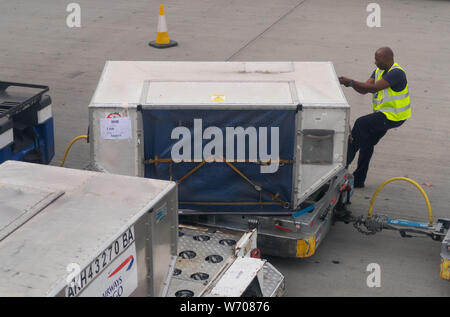 Gepäck handers Gepäck Fracht von Behältern von einem britischen Flugzeug Airways in London Heathrow Terminal 5 entladen Stockfoto
