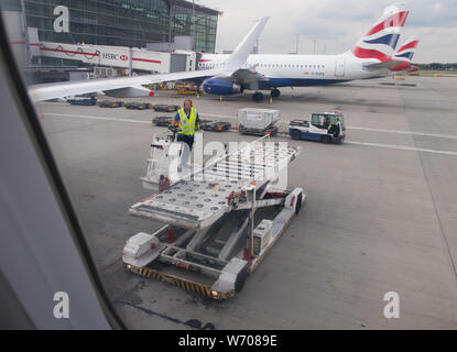 Gepäck handers Gepäck Fracht von Behältern von einem britischen Flugzeug Airways in London Heathrow Terminal 5 entladen Stockfoto