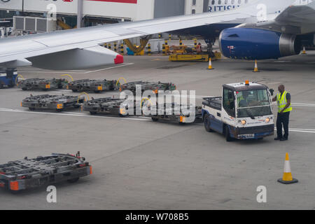 Gepäck handers Gepäck Fracht von Behältern von einem britischen Flugzeug Airways in London Heathrow Terminal 5 entladen Stockfoto