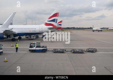 Gepäck handers Gepäck Fracht von Behältern von einem britischen Flugzeug Airways in London Heathrow Terminal 5 entladen Stockfoto
