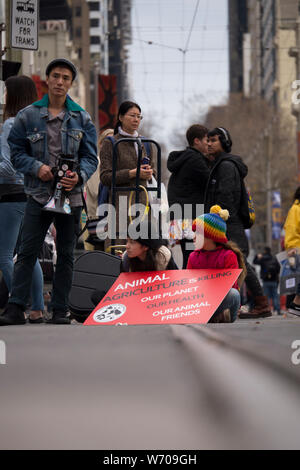 Zwei kleine Kinder sitzen auf Straßenbahnschienen mit roten Klima Not sign an Demonstration in der Innenstadt von Melbourne, Australien Klima protestieren. Stockfoto