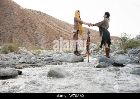 Zwei schamanischen Frauen in einer Priesterin Brücke Pose auf dem Fluss des Lebens. Stockfoto