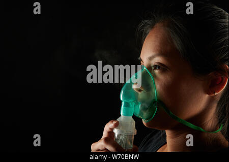 Nahaufnahme der Frau mit inhalationsmaske auf schwarzem Hintergrund Stockfoto