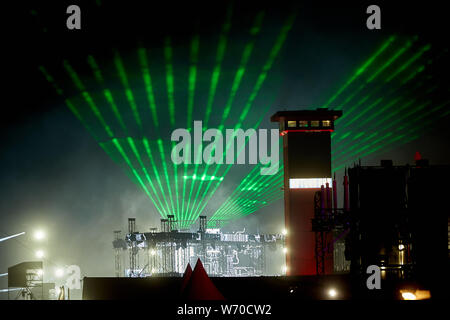 Kastellaun, Deutschland. 03 Aug, 2019. Das Licht der Bühne Laser können an den 25. Jahrestag der techno Festival "Nature One" im Hunsrück hinter der Wachturm der ehemaligen US-Raketenbasis "Pydna" gesehen werden. Zum Jubiläum die Organisatoren angekündigt, 350 DJs und Live Acts. Quelle: Thomas Frey/dpa/Alamy leben Nachrichten Stockfoto