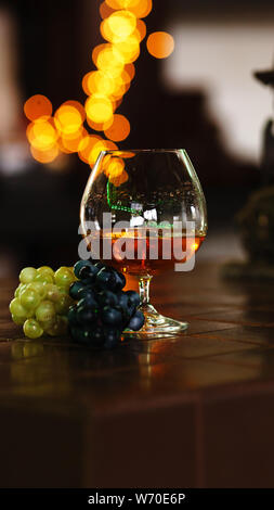 Französische Traubenbrände, starke alkoholische Getränk. Immer noch leben. Glas Cognac und Trauben. Service und Verkostung Konzept. Stockfoto