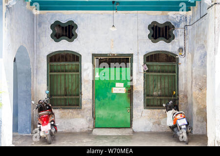 Motorräder im Eingang zu einem Sino portugiesische Architektur Stil Haus in der Altstadt von Phuket Town, Thailand geparkt Stockfoto