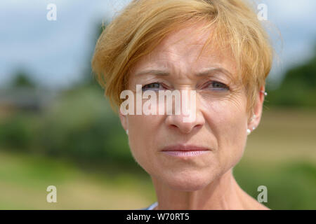 Schwerwiegende attraktive Frau mittleren Alters ernsthaft in die Kamera starrt in eine Nahaufnahme 7/8 Kopf geschossen Portrait im Freien Stockfoto
