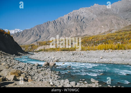 Türkisblaue Fluss durch Hunza Nagar Tal im Herbst Saison mit Blick auf Karakorum-gebirge fließt. Gilgit Baltistan, Pakistan. Stockfoto