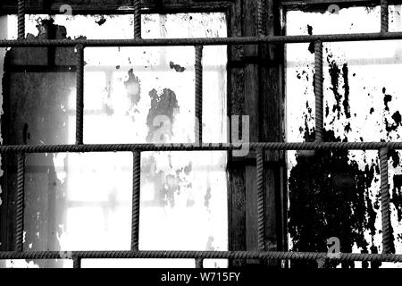 Alte Fenster weiss lackiert Farbe hinter einem rostigen Bars closeup, Schwarz und Weiß Stockfoto