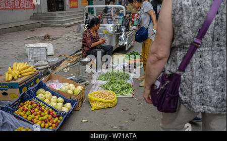 MISHAN, CHINA - Juli 27, 2019: Unbekannter Menschen vor Ort kaufen und verkaufen Produkte auf der Straße in Mishan. Mishan ist eine Stadt in der Stockfoto