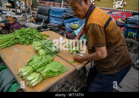 MISHAN, CHINA - Juli 27, 2019: Unbekannter Menschen vor Ort kaufen und verkaufen Produkte auf der Straße in Mishan. Mishan ist eine Stadt in der Stockfoto