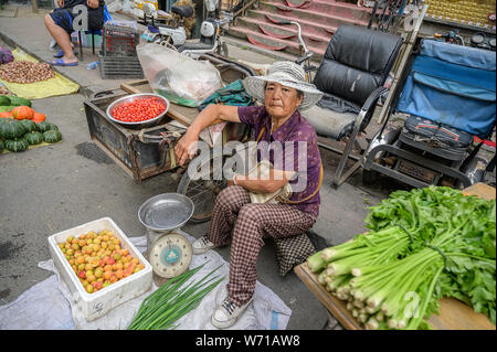 MISHAN, CHINA - Juli 27, 2019: Unbekannter Menschen vor Ort kaufen und verkaufen Produkte auf der Straße in Mishan. Mishan ist eine Stadt in der Stockfoto