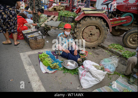 MISHAN, CHINA - Juli 27, 2019: Unbekannter Menschen vor Ort kaufen und verkaufen Produkte auf der Straße in Mishan. Mishan ist eine Stadt in der Stockfoto