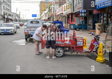 MISHAN, CHINA - Juli 27, 2019: Unbekannter Menschen vor Ort kaufen und verkaufen Produkte auf der Straße in Mishan. Mishan ist eine Stadt in der Stockfoto