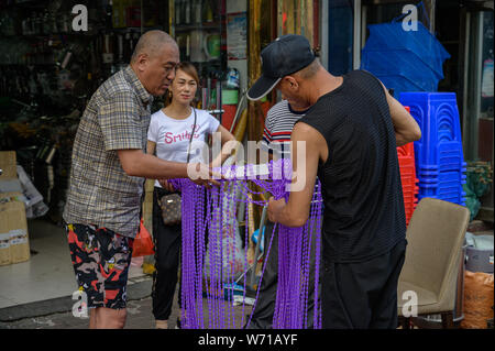 MISHAN, CHINA - Juli 27, 2019: Unbekannter Menschen vor Ort kaufen und verkaufen Produkte auf der Straße in Mishan. Mishan ist eine Stadt in der Stockfoto