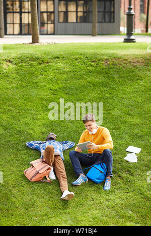 Hohen winkel Portrait von zwei Studenten liegen auf grünen Gras im Campus und Entspannen im Freien, kopieren Raum Stockfoto