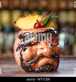 Pina Colada über Holz- Hintergrund garniert Ananas und Kirsche in ceramick Glas in Form der Karibik Piraten. Close-up Stockfoto