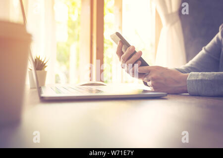 Business Frau mit Laptop Computer online Aktivität und Holding Telefon auf Holz Tisch. Stockfoto