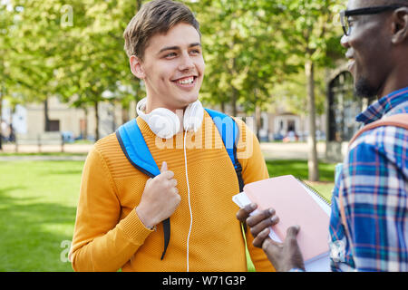 Taille bis Portrait von fröhlichen Student Gespräch mit afroamerikanischen Freund draußen in Campus, Raum kopieren Stockfoto