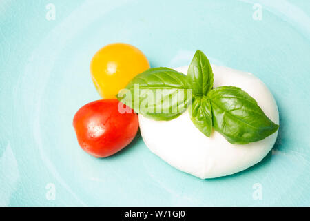 Mozzarella, Basilikum und Cherry Tomaten auf blauem Hintergrund Stockfoto