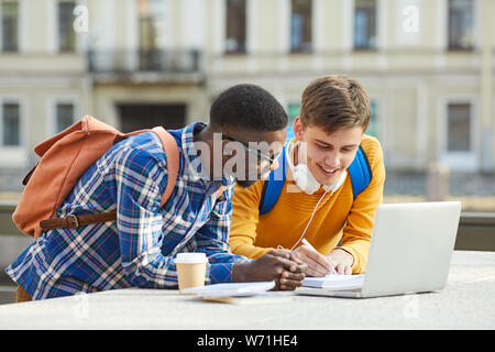 Taille, Porträt von zwei internationalen Studierenden gemeinsam Hausaufgaben zu machen stand draußen in den Campus, Raum kopieren Stockfoto