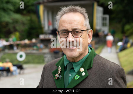 Clausthal Zellerfeld, Deutschland. 04 Aug, 2019. Rüdiger Kail, Vorsitzender des Heimatbund Oberharz, steht vor der Bühne der Jodler Wettbewerb im Harz. Die Jodler Wettbewerb ist einer der drei musikalische Wettbewerbe jährlich im Harz statt. Es ist, als eine wichtige Komponente in der Fortsetzung einer Jahrhunderte alten Volkslied Tradition betrachtet. Credit: Swen Pförtner/dpa/Alamy leben Nachrichten Stockfoto