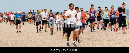 Babylon, New York, USA - 24. Juni 2019: Viele Leute, die eine Meile Rennen am Strand durch das Wasser am Robert Moose State Parks Sommer-Serie. Stockfoto