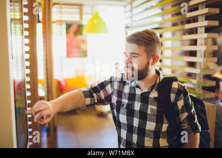 Ein Mann Bestellungen Essen im Touch Screen Terminal mit elektronischen Menü in Fast Food Restaurant. Stockfoto