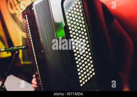 Close-up Musiker spielen auf dem Akkordeon vor einem schwarzen Hintergrund. Stockfoto