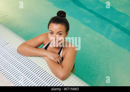 Porträt der schönen gemischten Rasse Frau oben Kamera, während im Pool posiert, Kopie Raum Stockfoto