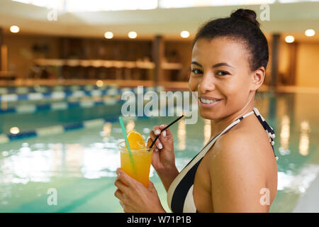 Porträt der schönen Frau trinkt Cocktail in Schwimmbad und lächelnd an Kamera, kopieren Raum Stockfoto