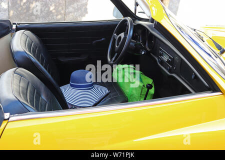 Nahaufnahme einer gelben Classic Cabrio mit einem womam Sonnenhut liegen auf dem Fahrersitz Stockfoto