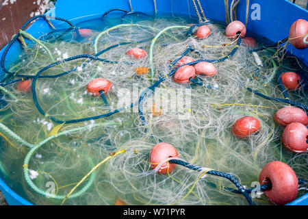 Selektiver Fokus Nahaufnahme der Fischernetz versunkenen in Blau gebrochen alte Wasser barrel. Marine Hintergrund, Foto auf der Insel von Ioannina, Griechenland Stockfoto