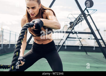 Frau tun Fitness Training mit Schlacht Seile auf im freien Fitnessraum Stockfoto