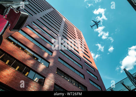 Suchen zwischen Büro- oder Wohngebäude am blauen Himmel mit dem Flugzeug vorbei an Aufwand zwischen den Wolken Stockfoto