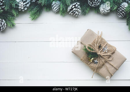 Geschenkbox in Kraftpapier mit Rand aufgewickelt Kiefer auf weißem Holz Hintergrund. Für Weihnachten oder Eibe Konzepte Ideen. Flach template Design Stockfoto