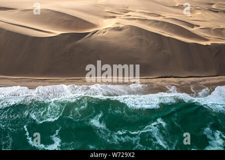 Luftaufnahme der Skelettküste Sanddünen treffen die Wellen der Atlanic Ocean. Skeleton Coast, Namibia. Stockfoto