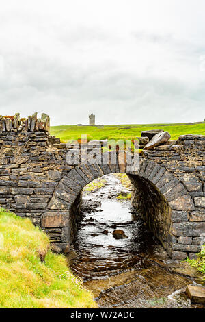 Alte steinerne Brücke mit dem Schloss Doonagore im Hintergrund An der Küste zu Fuß auf dem Weg von Doolin in die Klippen von Moher, die wilden Atlantik Weg Stockfoto