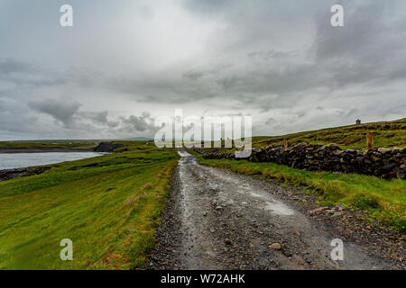 Wunderschöne Aussicht auf einem Pfad zwischen dem Meer und einem Stein Zaun an der Küste zu Fuß auf dem Weg von Doolin in die Klippen von Moher, die wilden Atlantik Weg Stockfoto